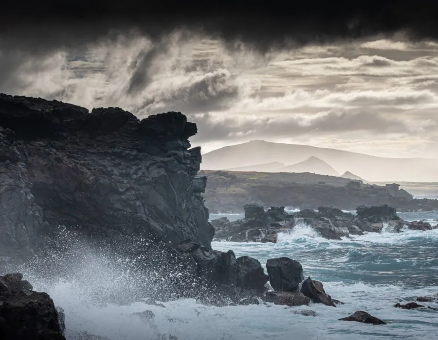 Waves crashing against rocks with dark sky above