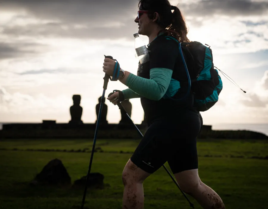 Female participant running past grassy fields with statues in the distance