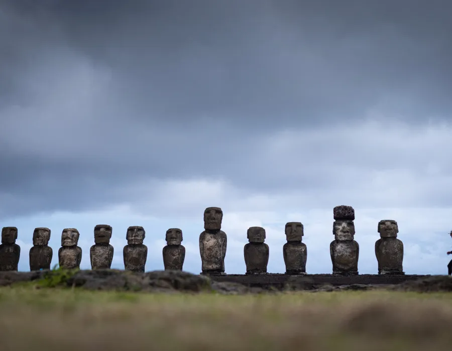Event participants running along a line of statues, with a grey, cloudy sky above