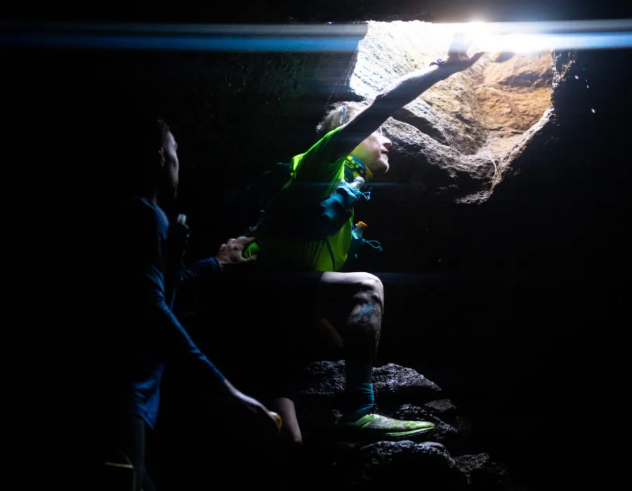 Participants peering through a hole in a dark cave