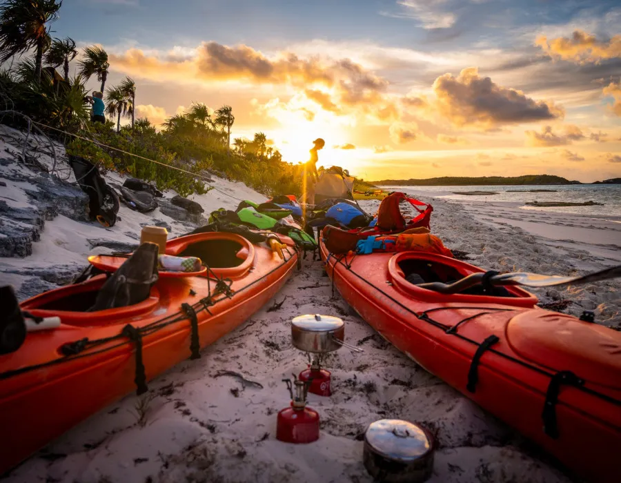 Kayaks placed on a sandy beach next to the water