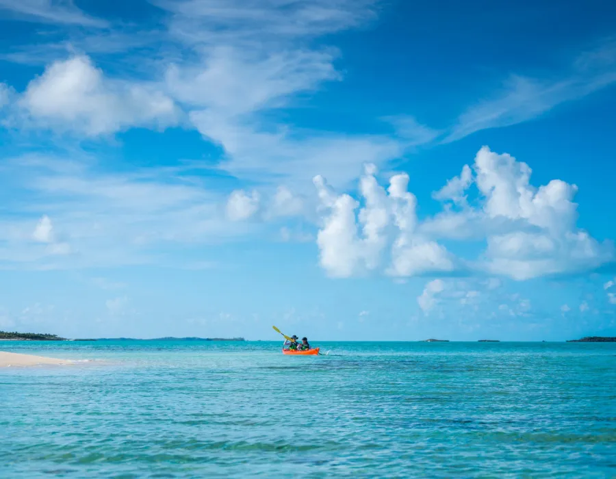 Two participants kayak with a bright sky above them and still waters below