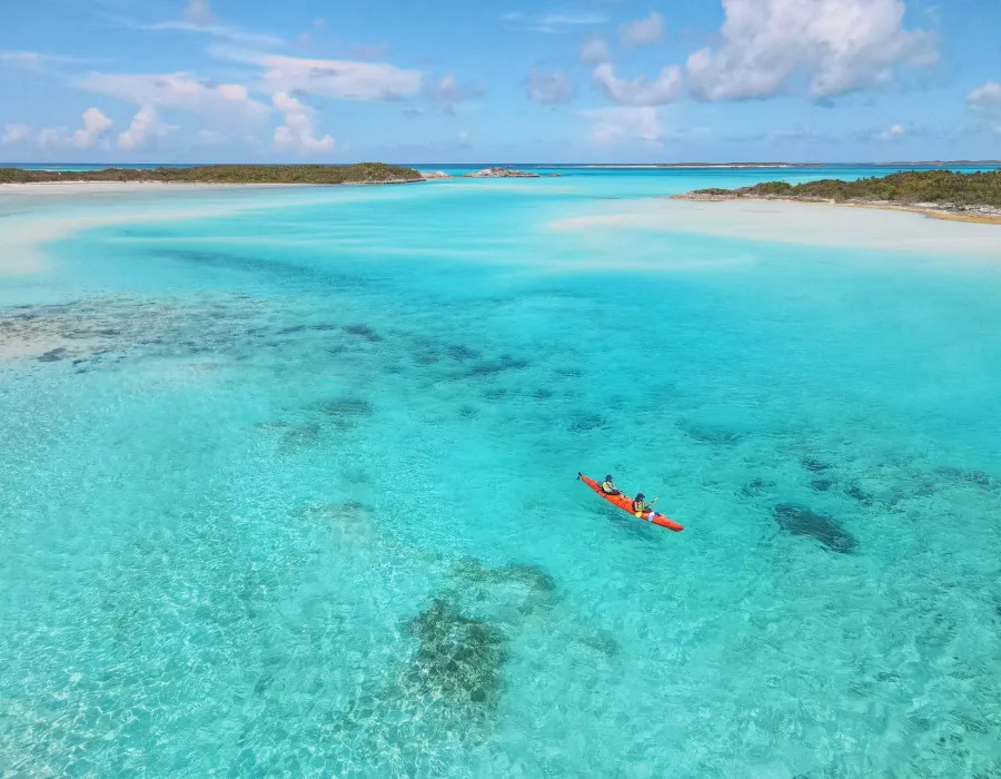 Participants kayaking through clear water with islands behind them
