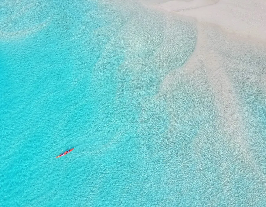 Aerial view of kayak moving through clear, shallow water