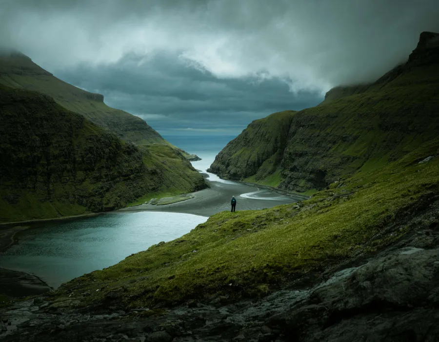 Participant stood on rocky and green terrain, looking out to dark water