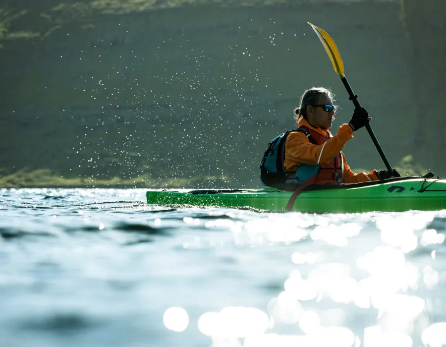 Man wearing a colourful coat and rucksack and kayaking