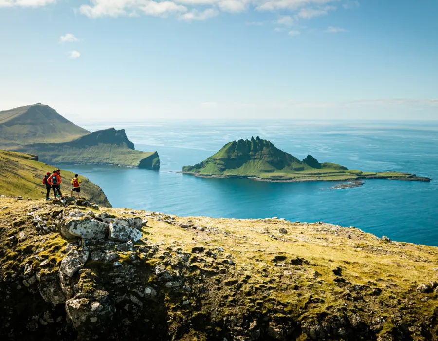 Participants stand on rocky ledge, looking out to cliffs and clear, blue waters
