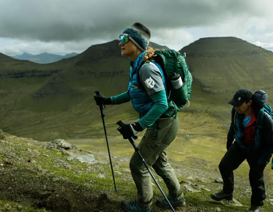 Man and woman hiking on grassy and rocky terrain