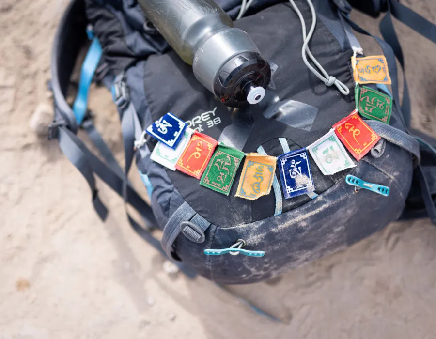 Rucksack on a sandy beach with a bottle lying on top