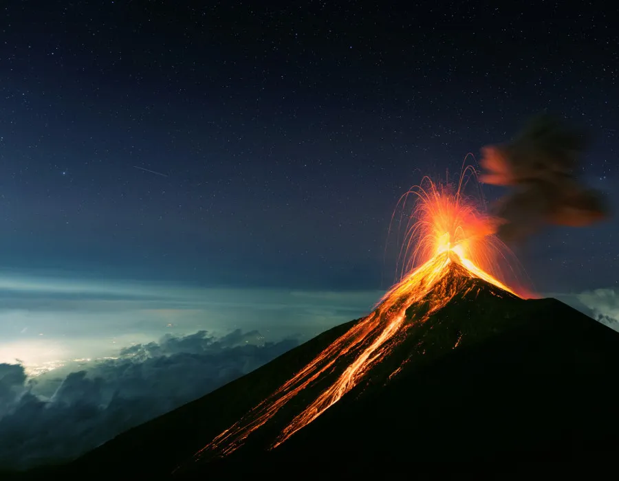 Volcano erupting with bright lava as a still, starry sky lies above