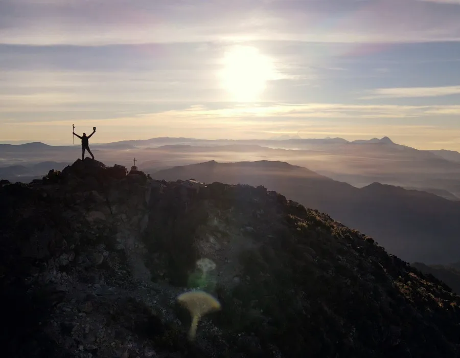 Participant stood with their arms in the air on top of rocky mountain