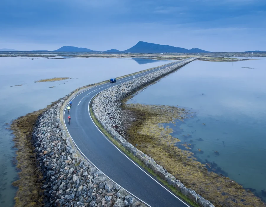 Cyclist riding along road with water either side