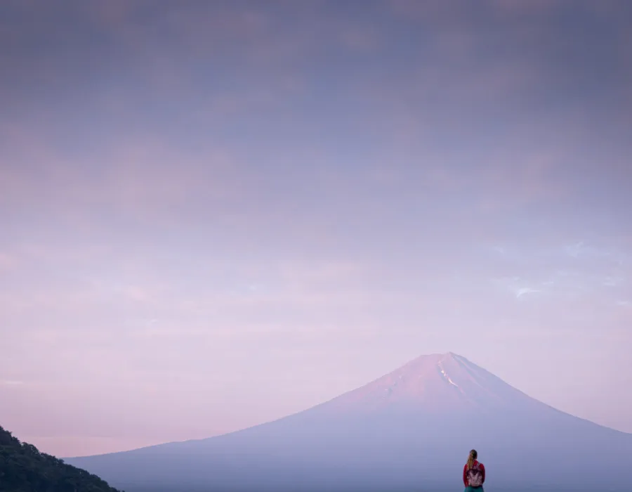 Woman stood infront of Mount Fuji with a colourful sky above