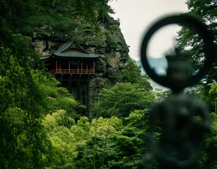 Traditional Japanese building attached to cliff and surrounded by greenery
