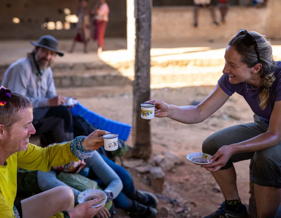 Man and woman laughing and drinking from small cups and saucers