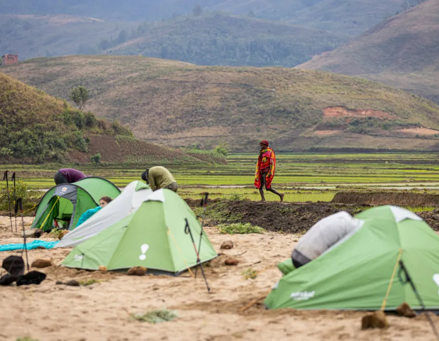 Tents pitched on sand and rolling hills in the background