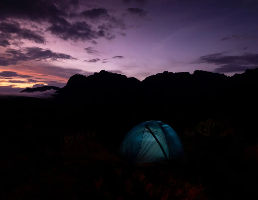 Illuminated tent under dark, purple sky