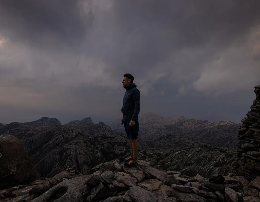 Man stood on rocks with grey sky behind him
