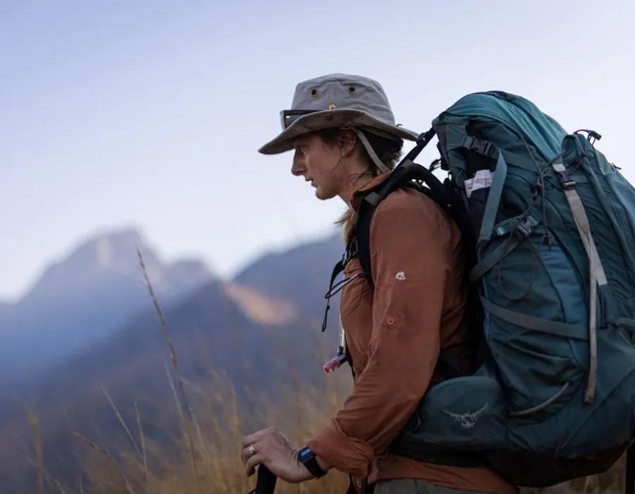 Woman hiking through grassland wearing a rucksack