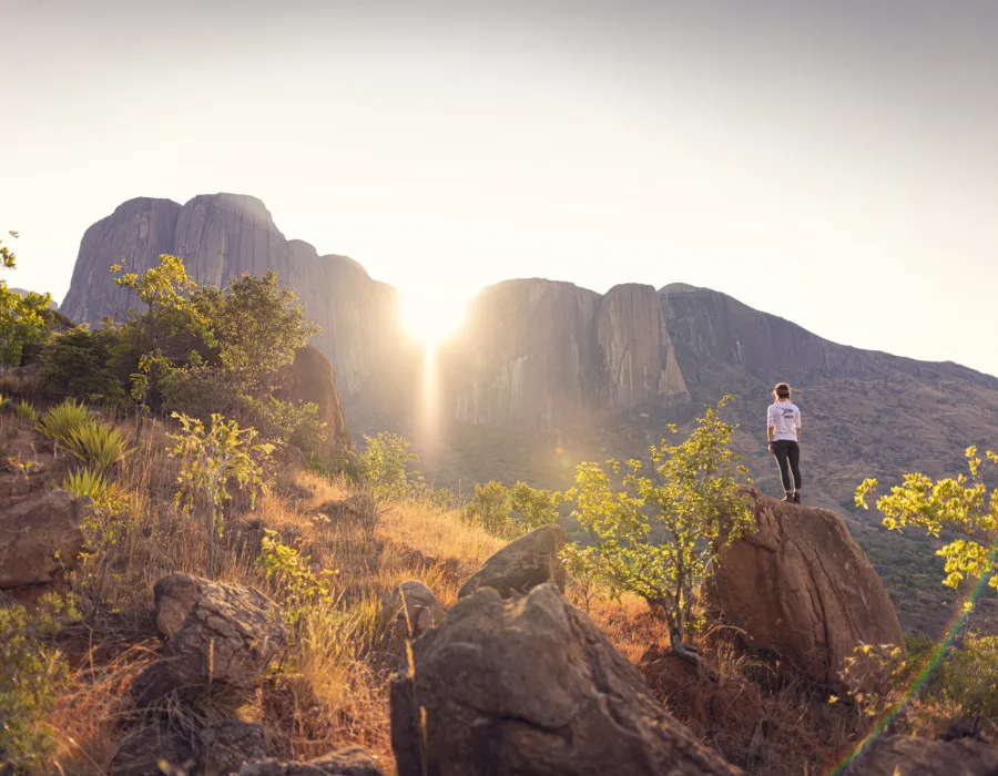 Woman stood on rocks and looking up at mountains