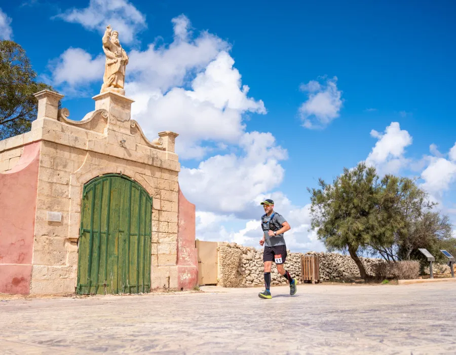 Man running past grand building entrance in sunshine