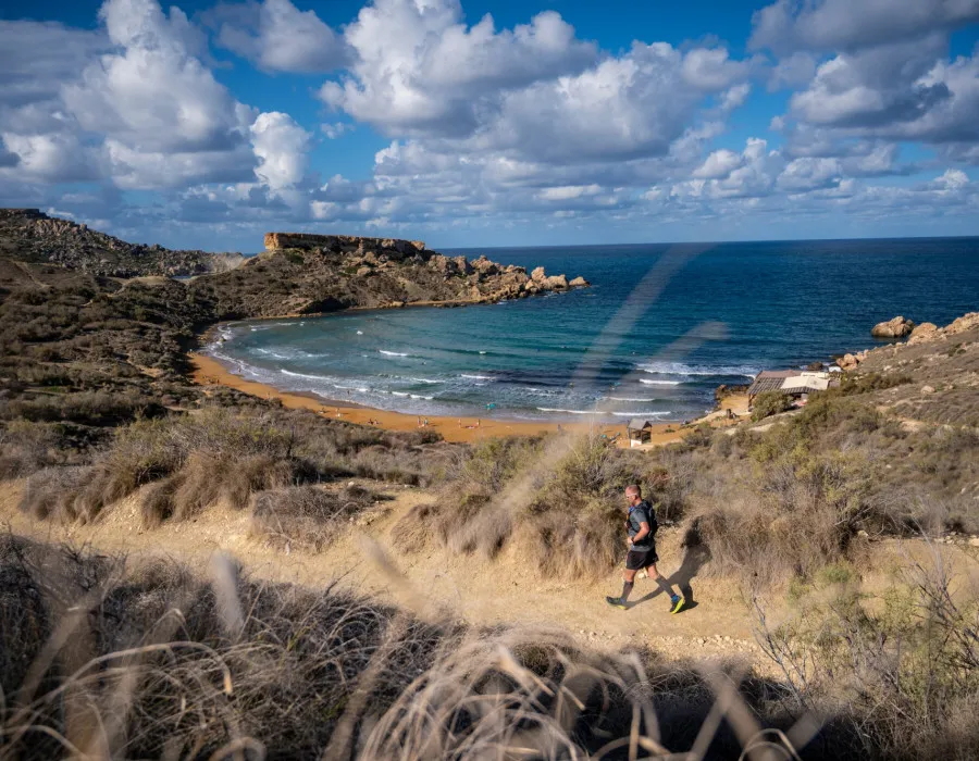 Man running along sandy and rocky coastline