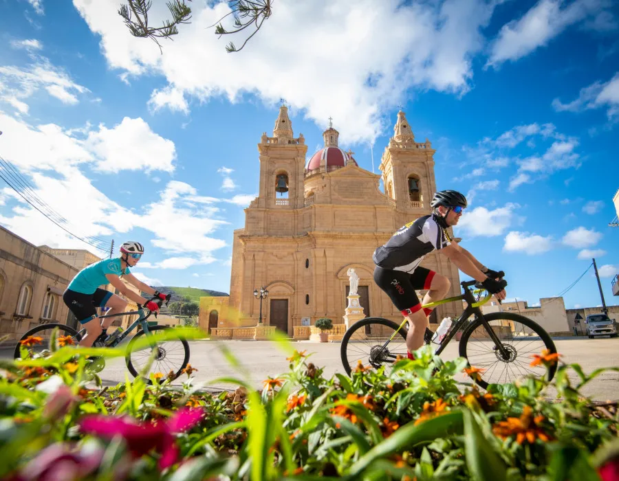 Cyclists ride past grand building