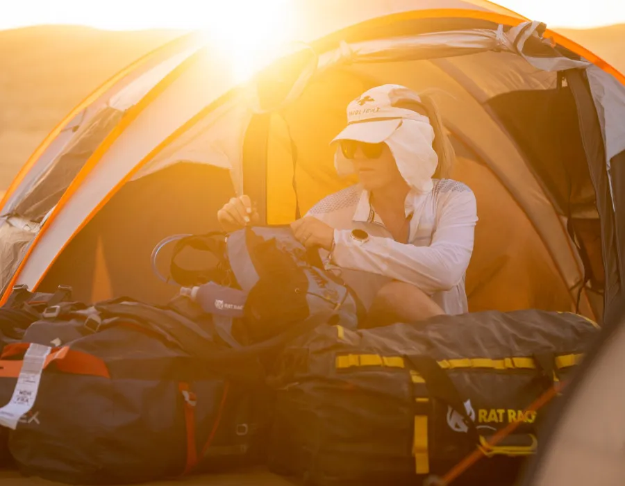Woman sat in tent and zipping up rucksack