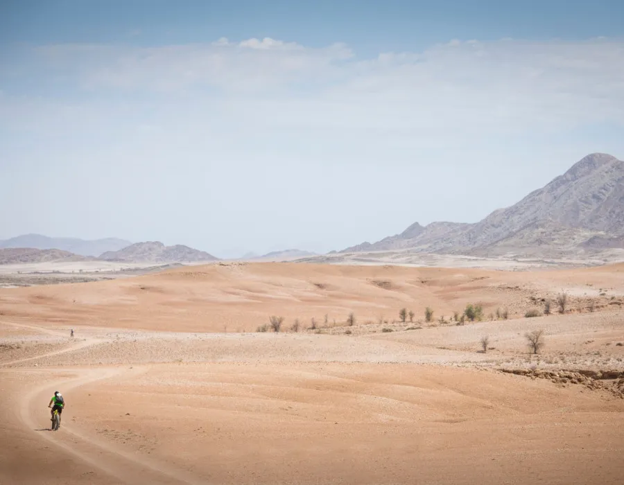 Participant cycling along sandy, desert track