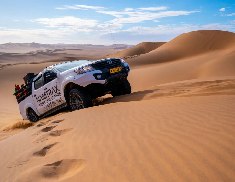 Car driving up smooth sand dunes