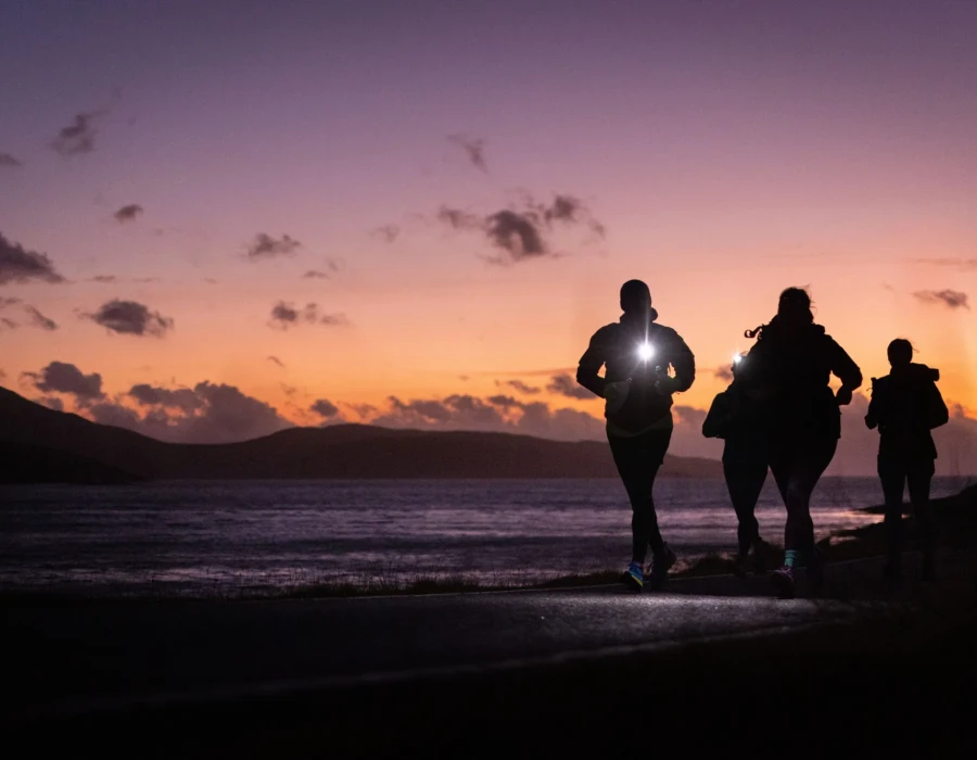 People running at night with colourful sky behind