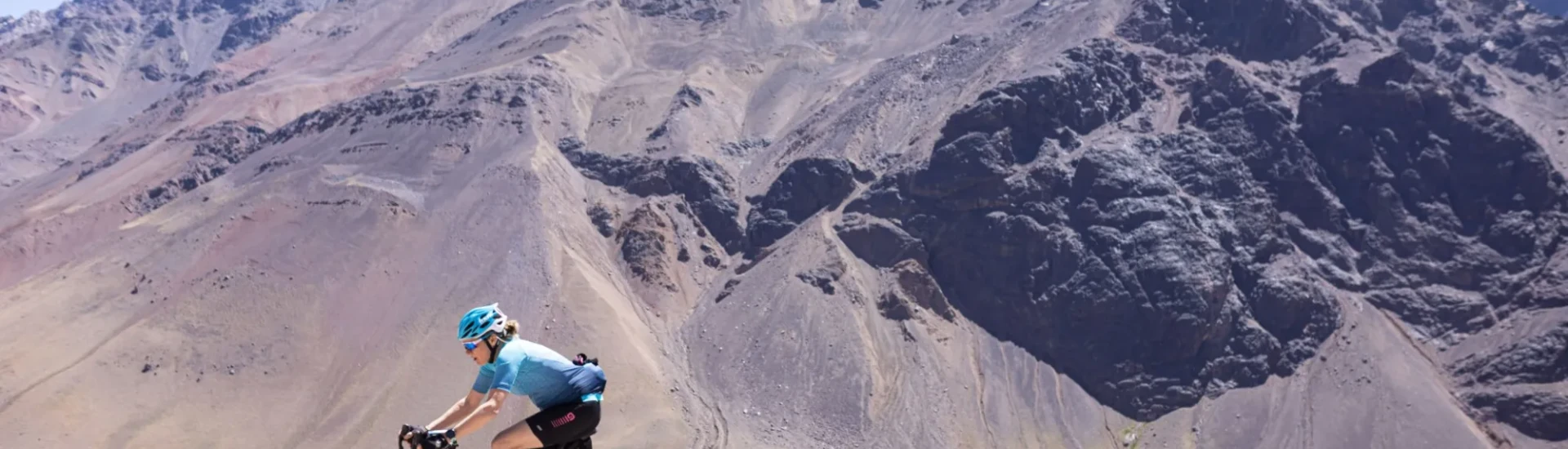 Cyclist riding along rocky path next to mountains