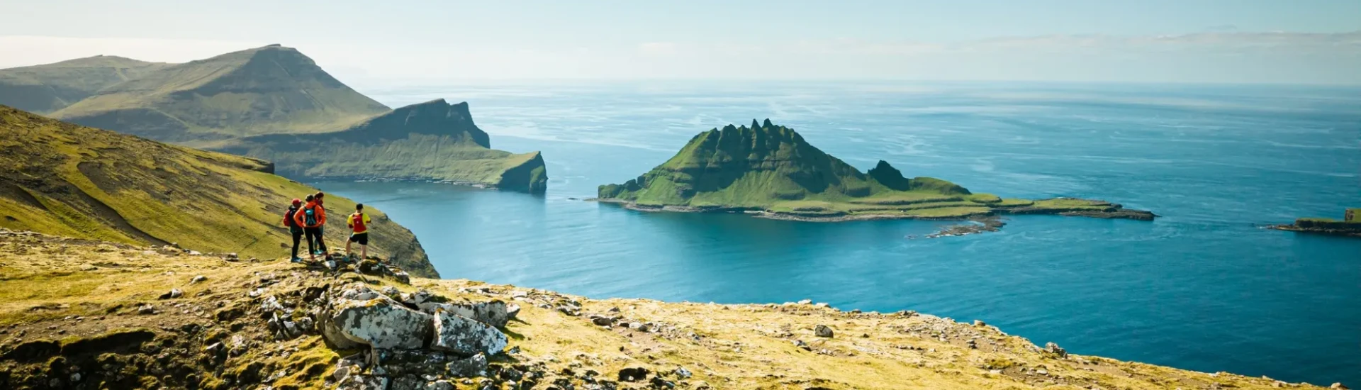 Participants stand on rocky ledge, looking out to cliffs and clear, blue waters