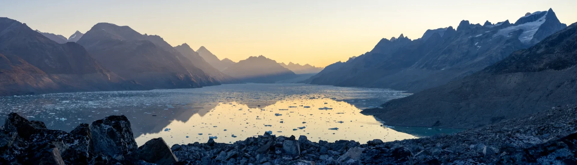 Floating ice in clear water and snowy mountains in the background
