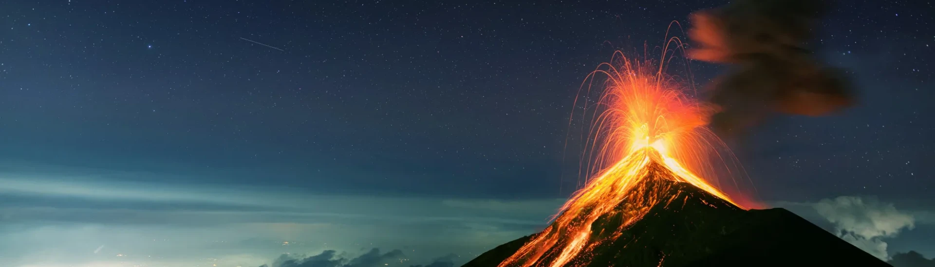 Volcano erupting with bright lava as a still, starry sky lies above