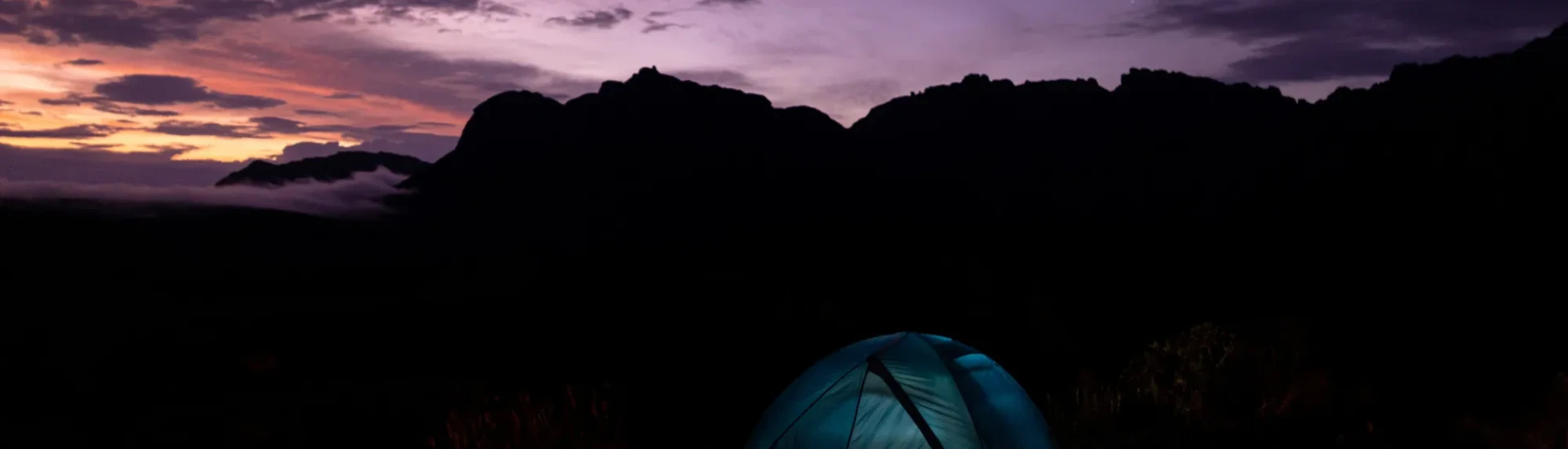Illuminated tent under dark, purple sky