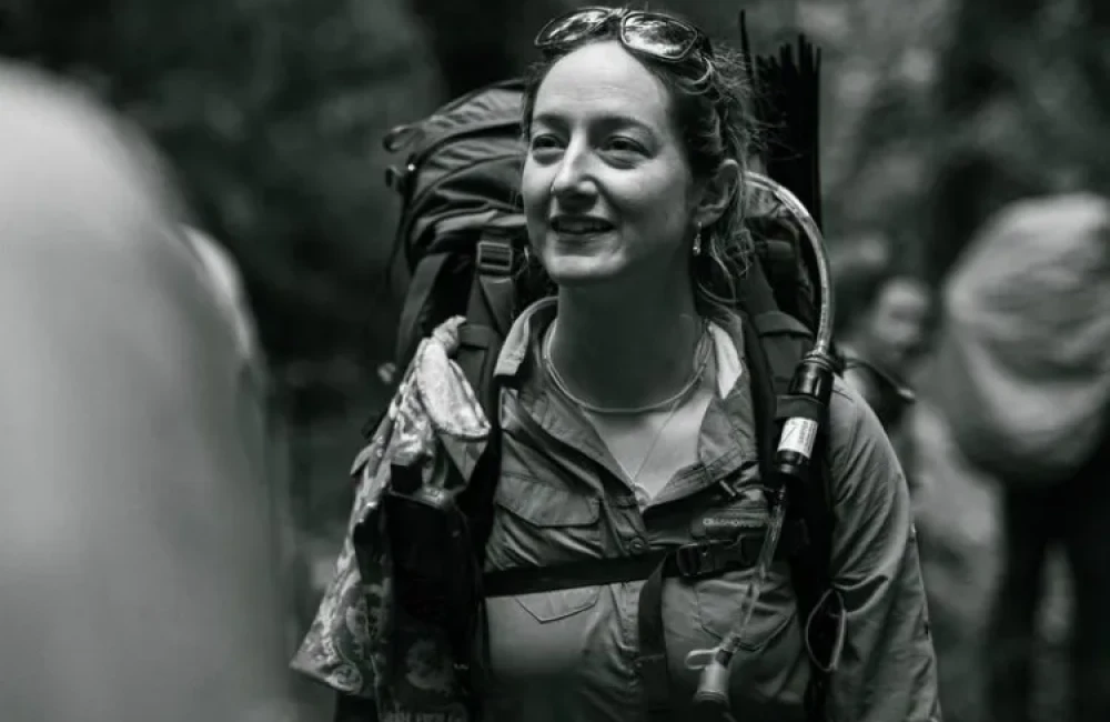 Woman wearing rucksack and smiling in jungle