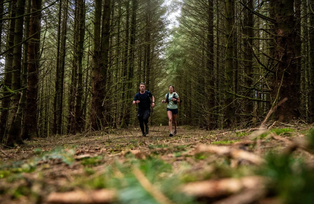Man and woman running through forest