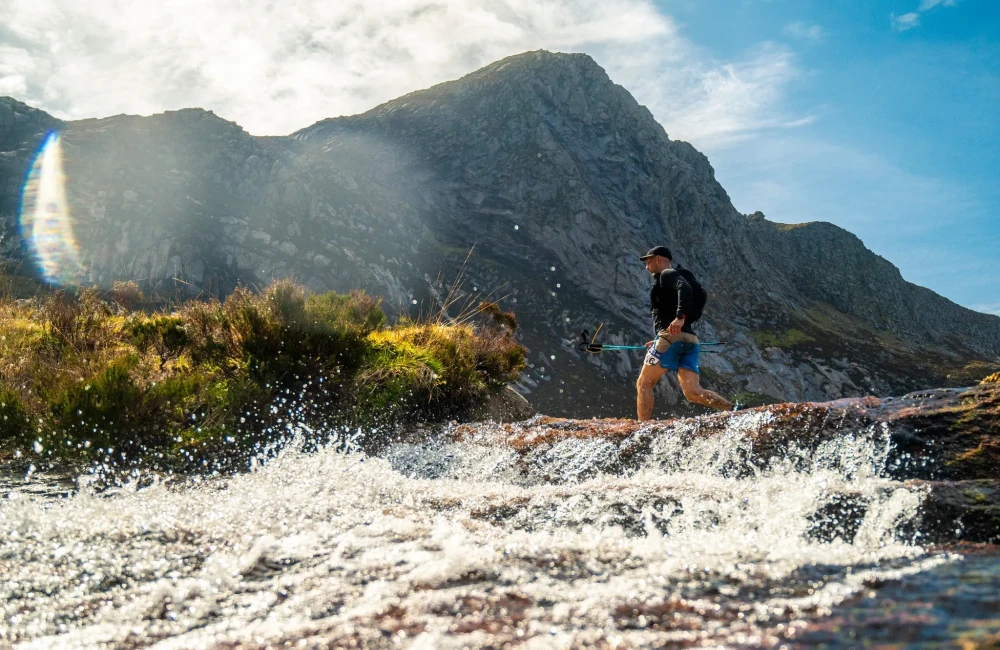Man running over water with mountains behind