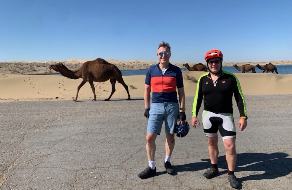 Men smiling and stood infront of camels