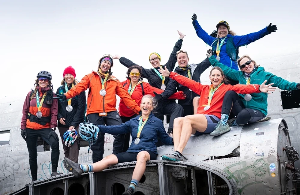 Group of women on plane wreck with medals around their necks and smiling