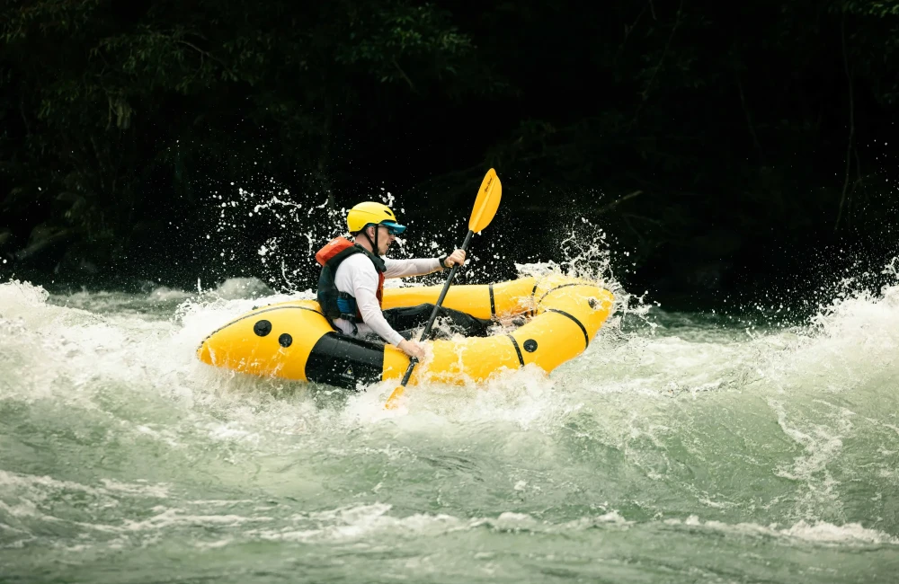Man rafting through water as it splashes against him