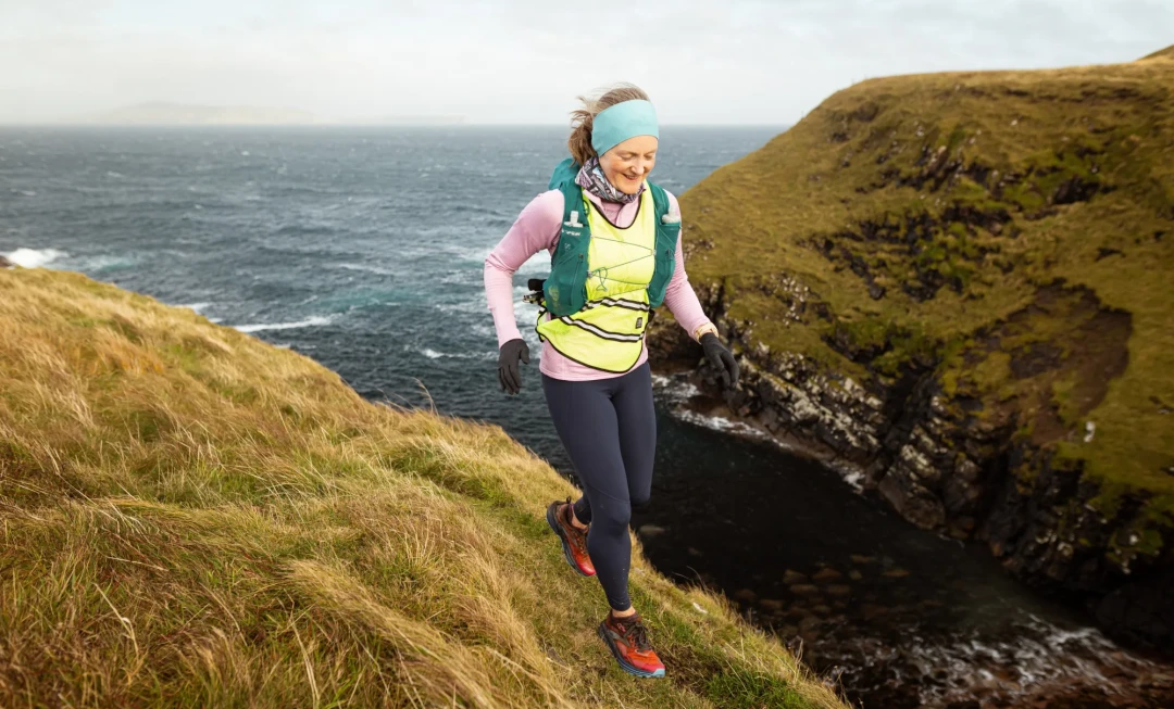 Woman running along grassy coastline