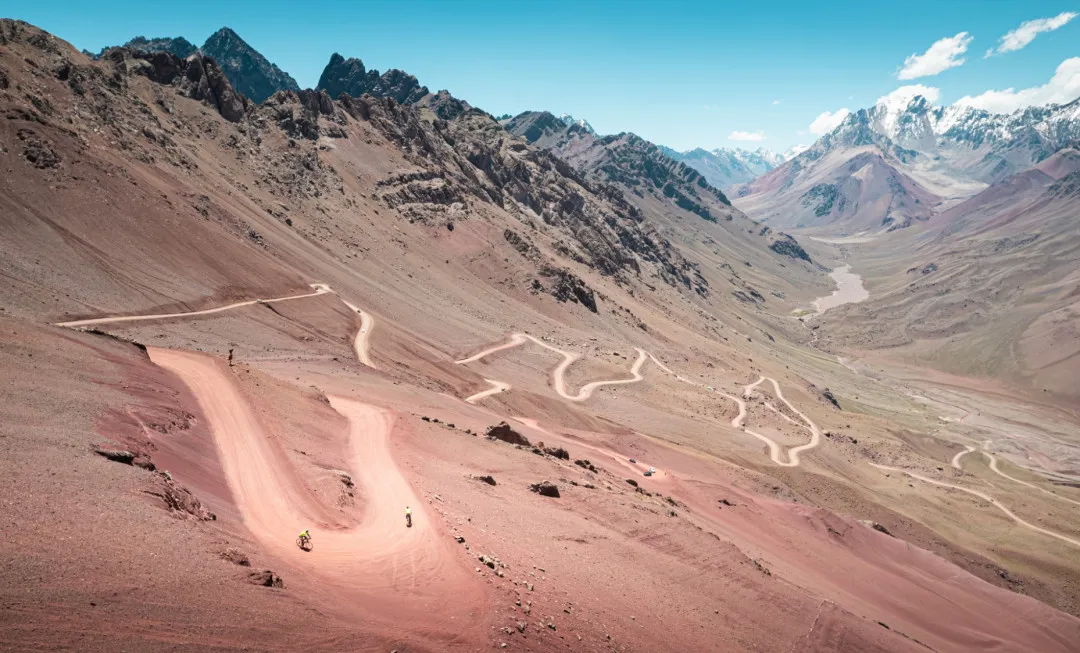 Winding road on dusty terrain with mountains behind