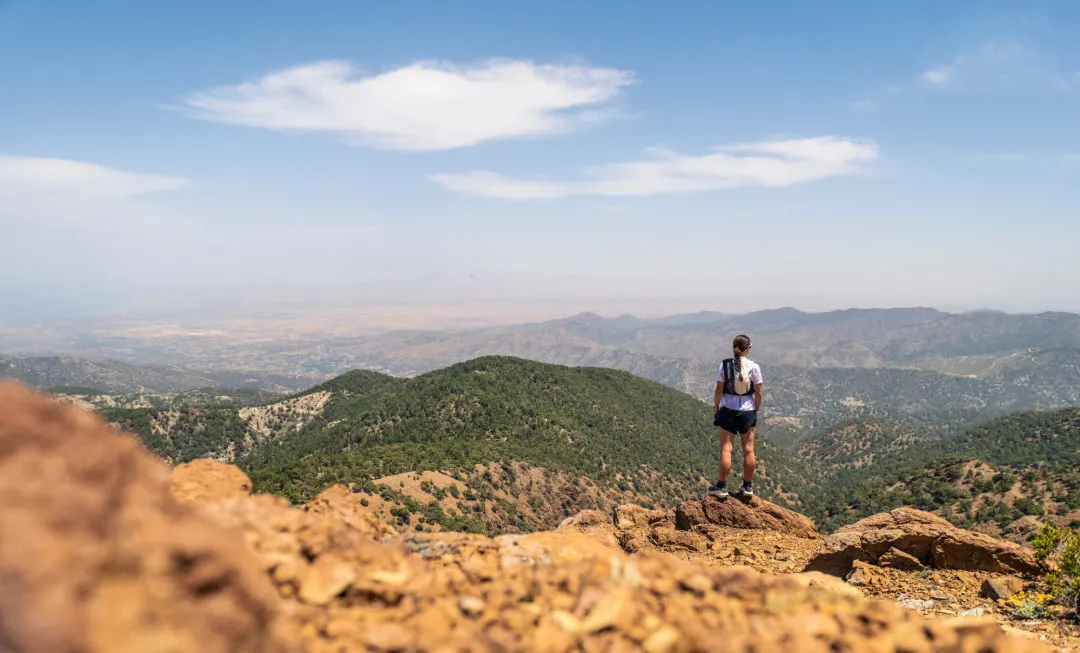 Woman looking out onto rolling mountains, with sparse greenery