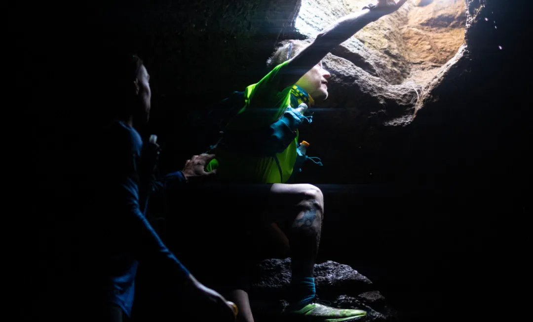 Participants peering through a hole in a dark cave