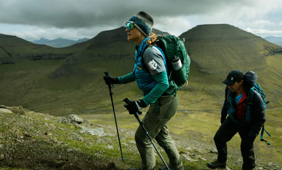 Man and woman hiking on grassy and rocky terrain