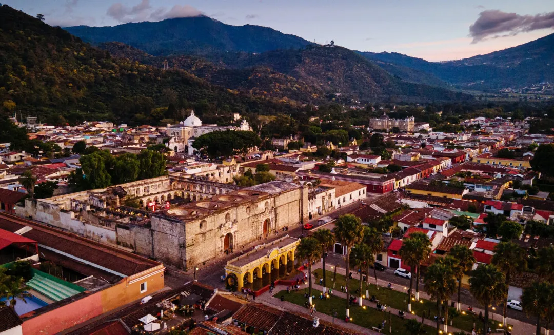 Colourful town with mountains in the background, covered in trees