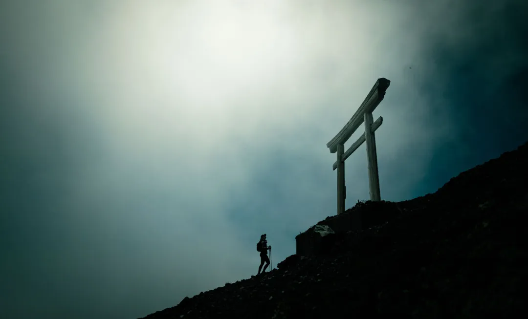 Participant stood on dark, rocky slope with a grey sky behind