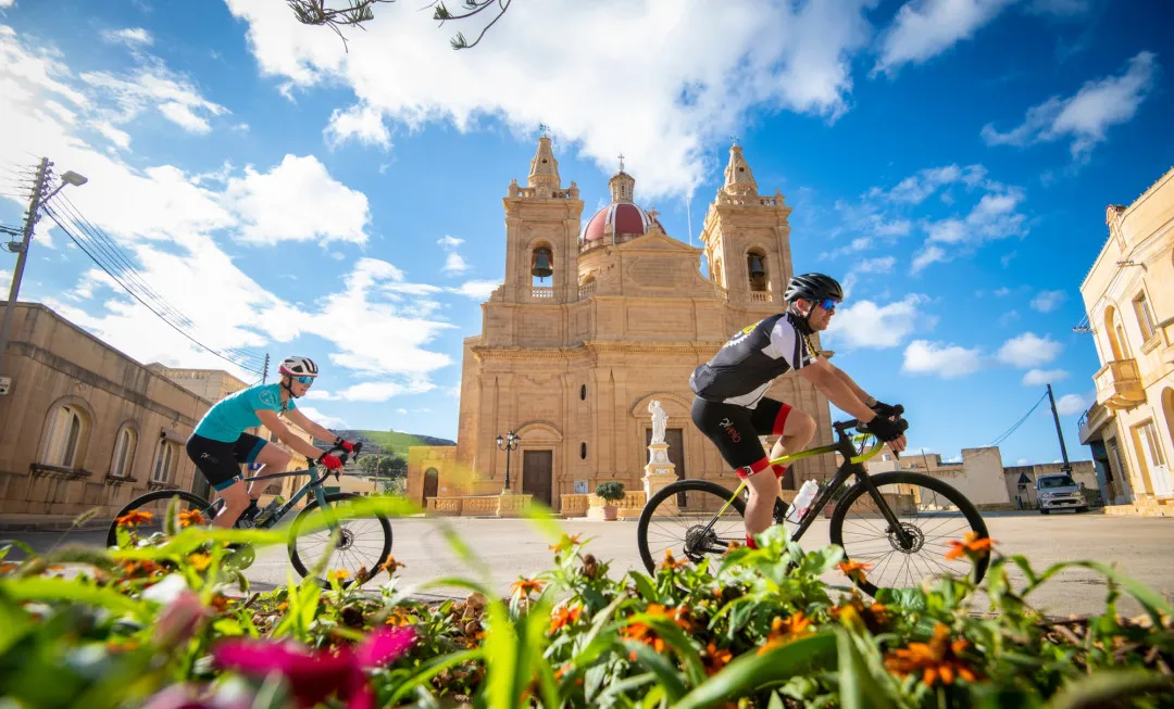 Cyclists ride past grand building